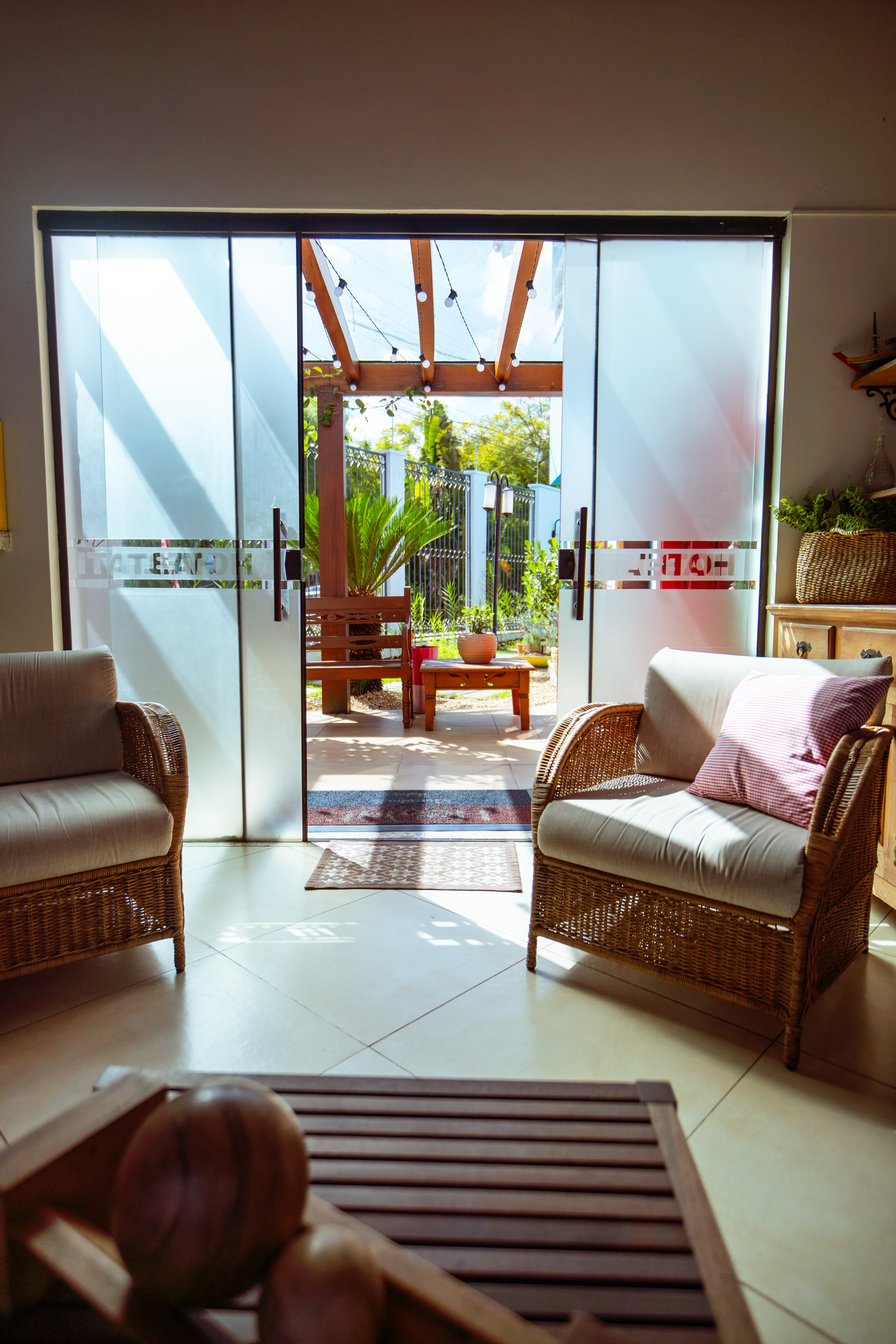 Lobby com poltronas de palhinha e vista para o jardim