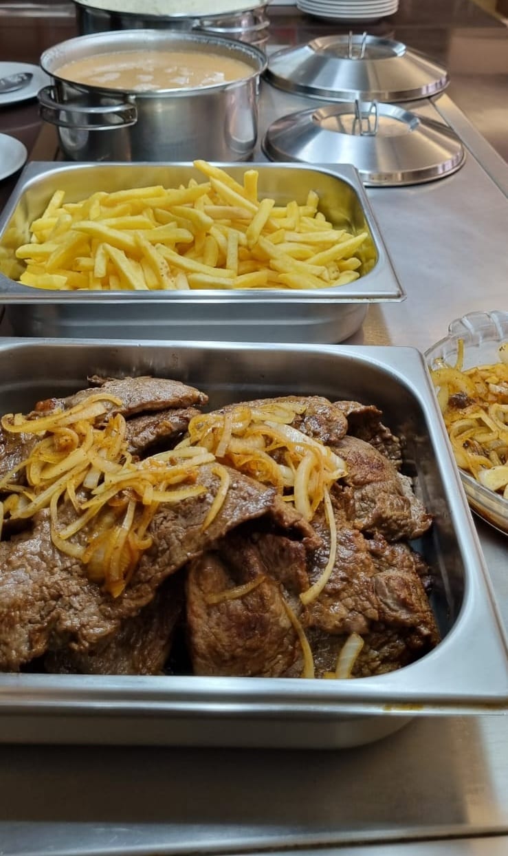 Bifes acebolados e batata frita no buffet