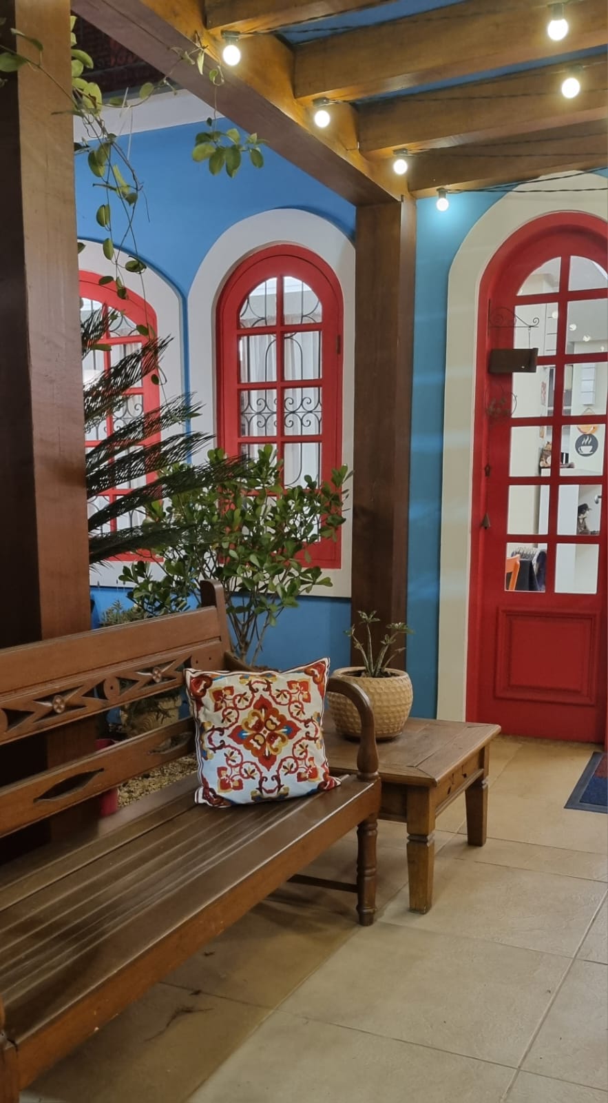Varanda com bancos de madeira e plantas no Habtati Hotel